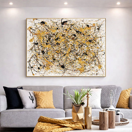 Gold abstract drip painting with black splatter framed above modern sofa in neutral living room