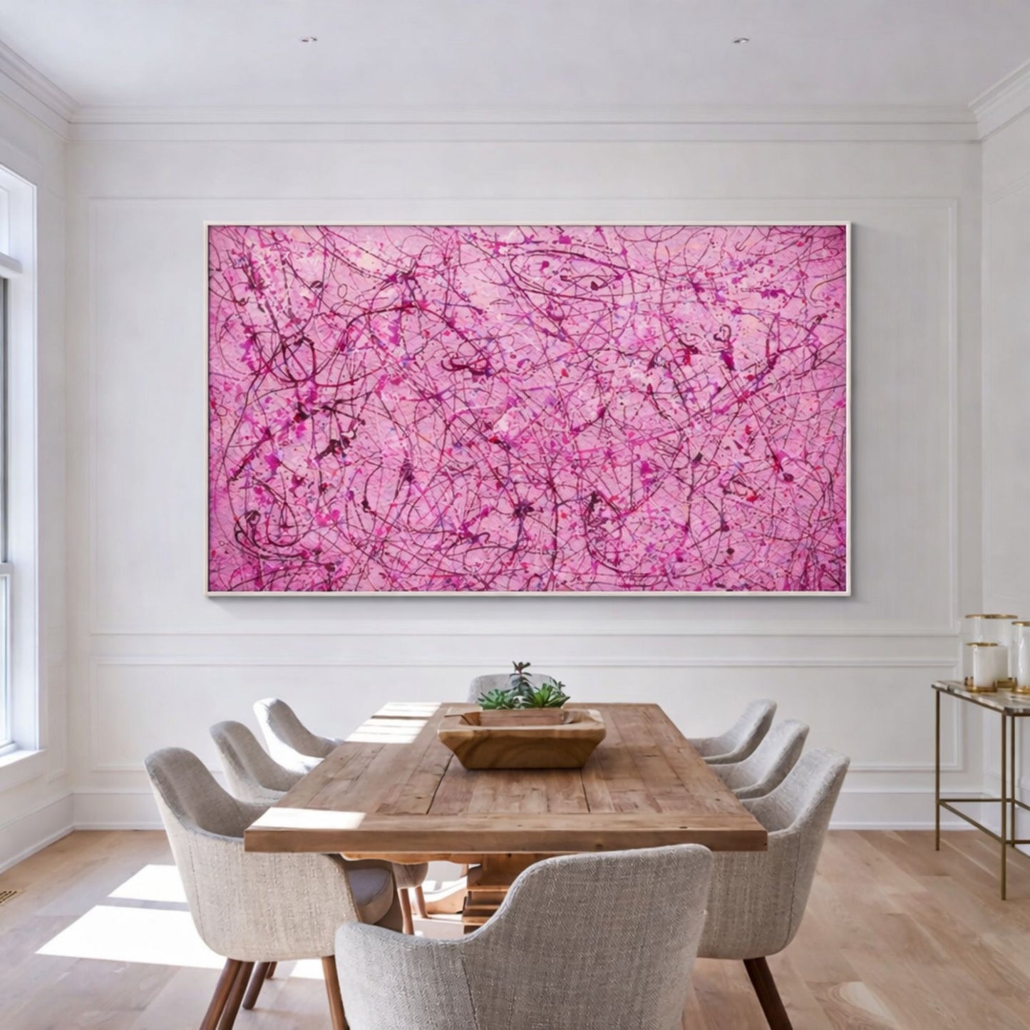 Pink abstract drip artwork with expressive lines displayed above wooden dining table