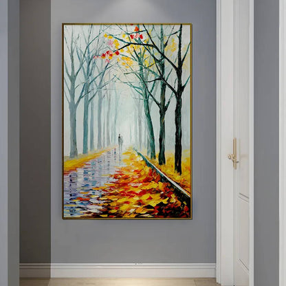 Room mockup. A path recedes between bare dark trees, with orange and yellow fallen leaves and a pale misty blue-green distance.