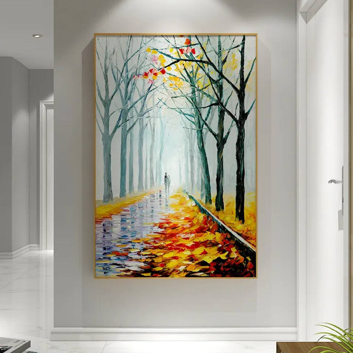 Room mockup. A path recedes between bare dark trees, with orange and yellow fallen leaves and a pale misty blue-green distance.