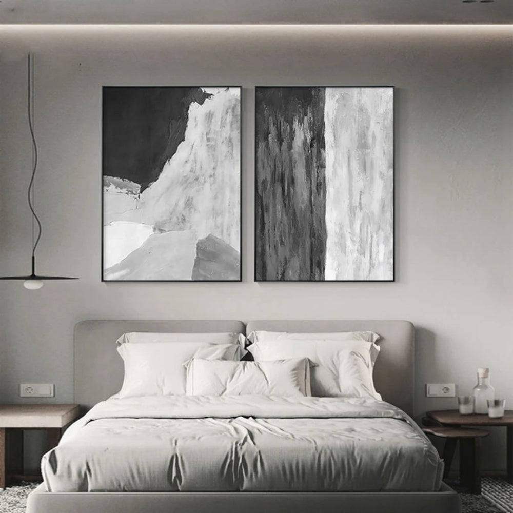 Room mockup showing pair of monochrome abstracts, one with a broad curved white area beneath black and one with vertical grey-white streaks.