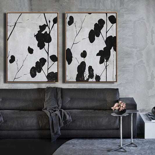 Room mockup showing two panels of black leaf silhouettes on thin branches against pale grey textured backgrounds.