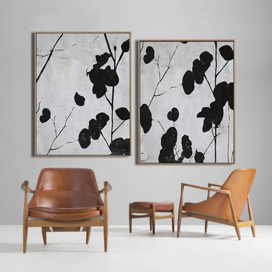 Room mockup showing two panels of black leaf silhouettes on thin branches against pale grey textured backgrounds.