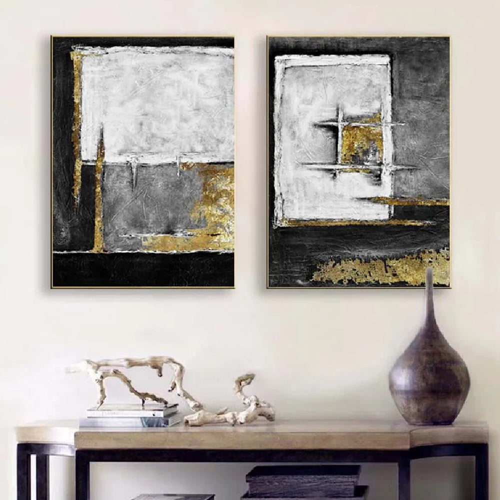 Room mockup showing two textured abstract panels with black, white and grey geometric fields and gold-coloured accents.