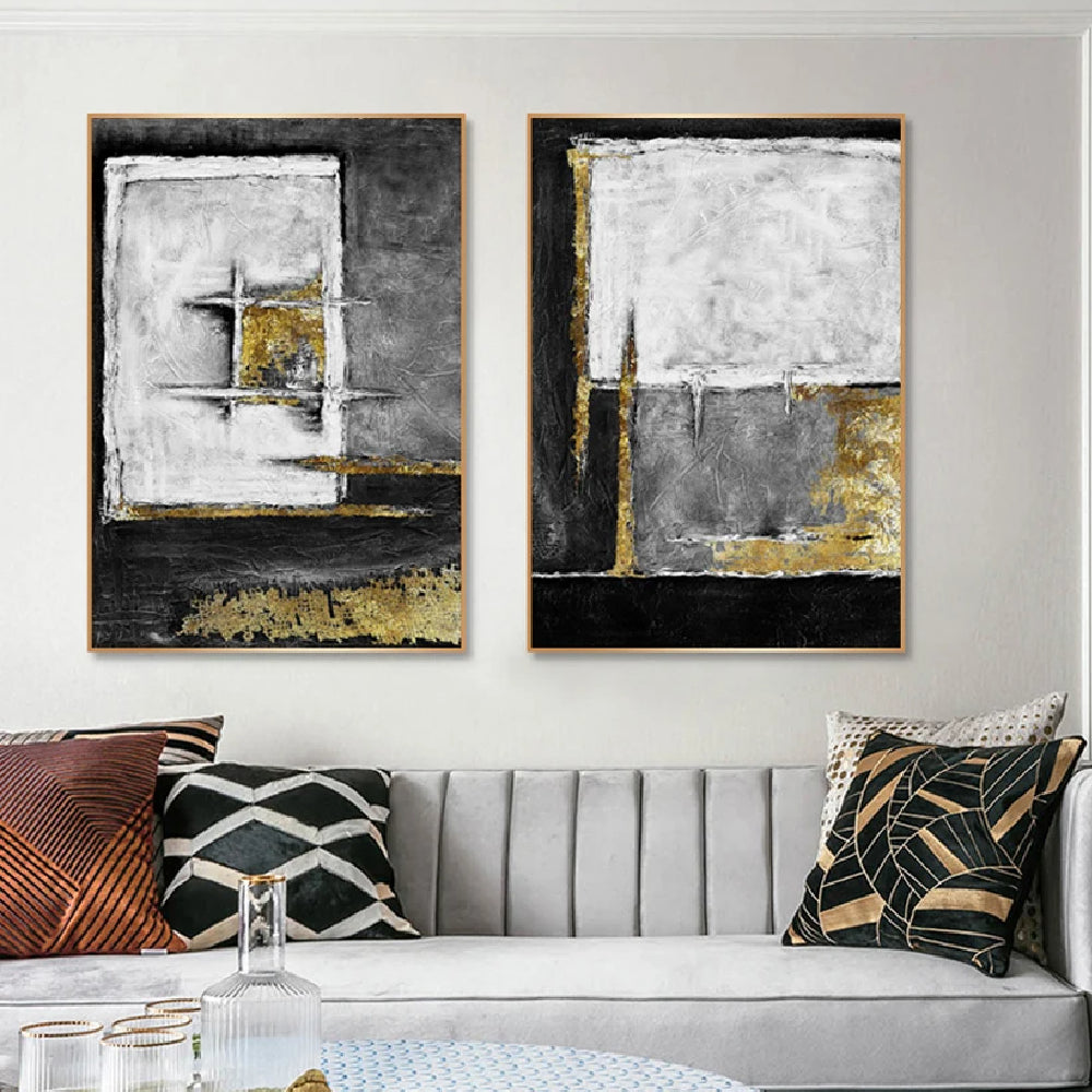 Room mockup showing two textured abstract panels with black, white and grey geometric fields and gold-coloured accents.