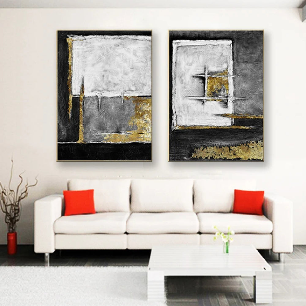 Room mockup showing two textured abstract panels with black, white and grey geometric fields and gold-coloured accents.