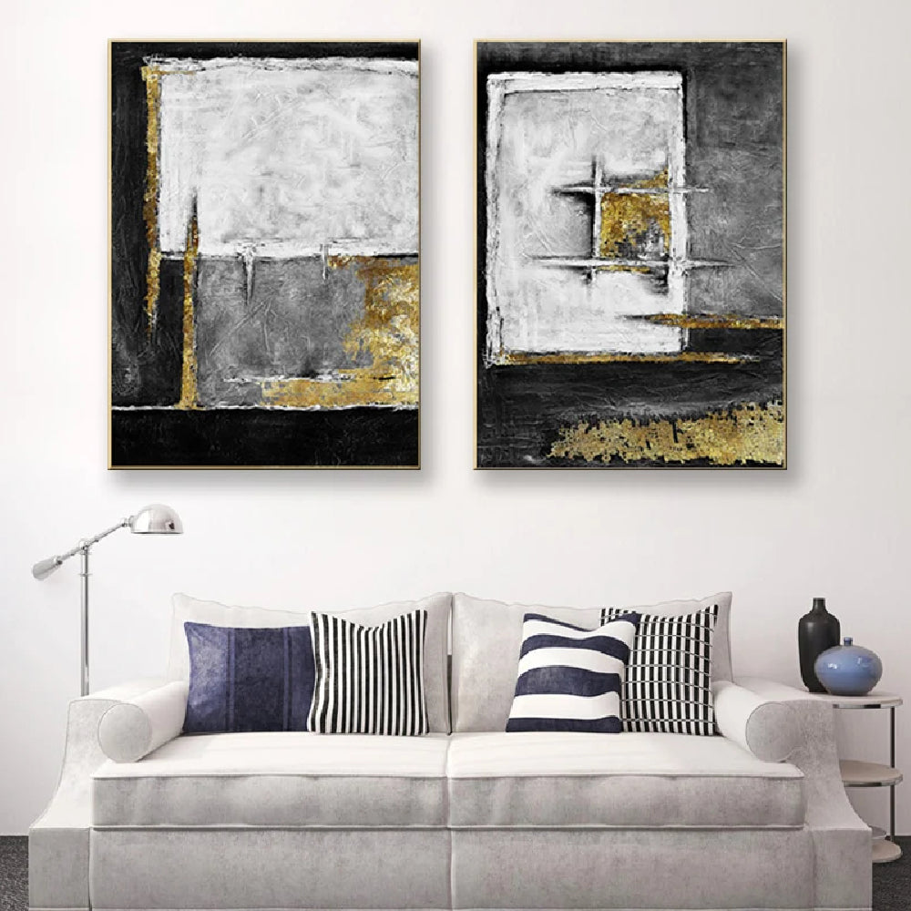 Room mockup showing two textured abstract panels with black, white and grey geometric fields and gold-coloured accents.