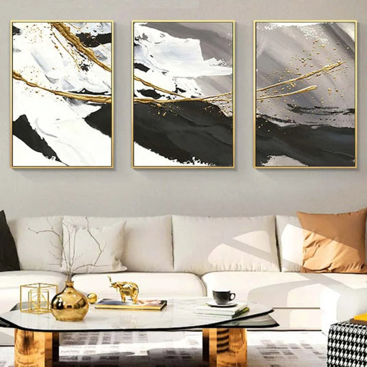 Room mockup showing three abstract panels with broad black, white and grey strokes crossed by narrow gold-coloured lines.
