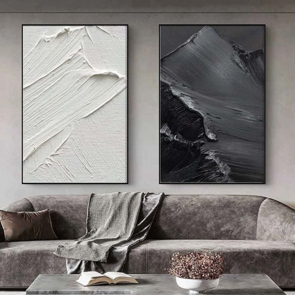 Room mockup showing two monochrome panels with broad raised sweeping brush marks, one white and one charcoal grey.