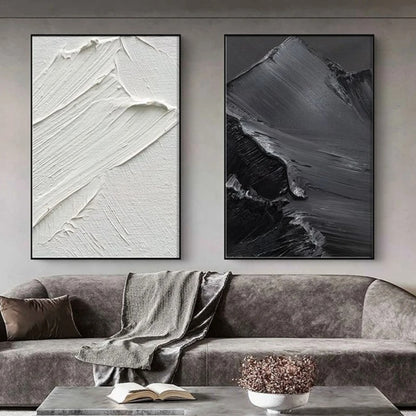 Room mockup showing two monochrome panels with broad raised sweeping brush marks, one white and one charcoal grey.