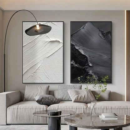 Room mockup showing two monochrome panels with broad raised sweeping brush marks, one white and one charcoal grey.