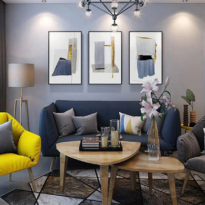 Room mockup showing three minimalist white panels with blue-grey geometric shapes, narrow gold-coloured strips and fine black lines.