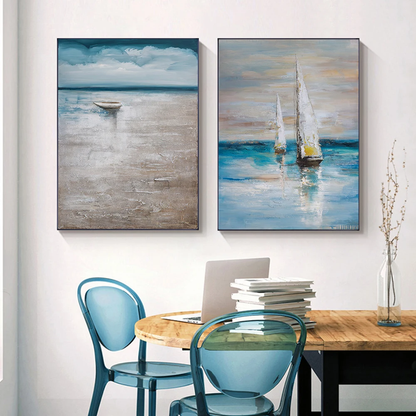 Room mockup showing pair of muted blue and grey seascapes, one with a small boat beneath clouds and one with white-sailed boats.