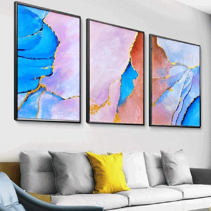 Room mockup showing three abstract panels with vivid blue, pale pink and coral flowing fields divided by thin gold-coloured lines.