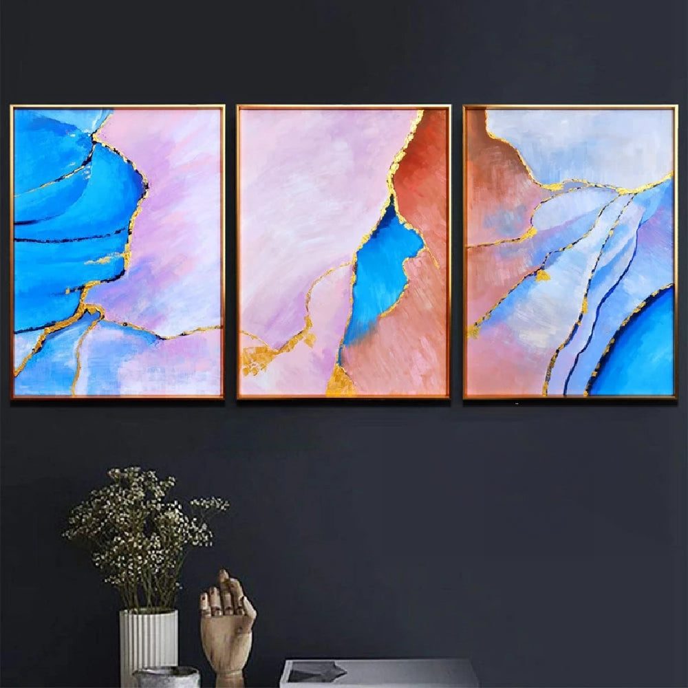 Room mockup showing three abstract panels with vivid blue, pale pink and coral flowing fields divided by thin gold-coloured lines.