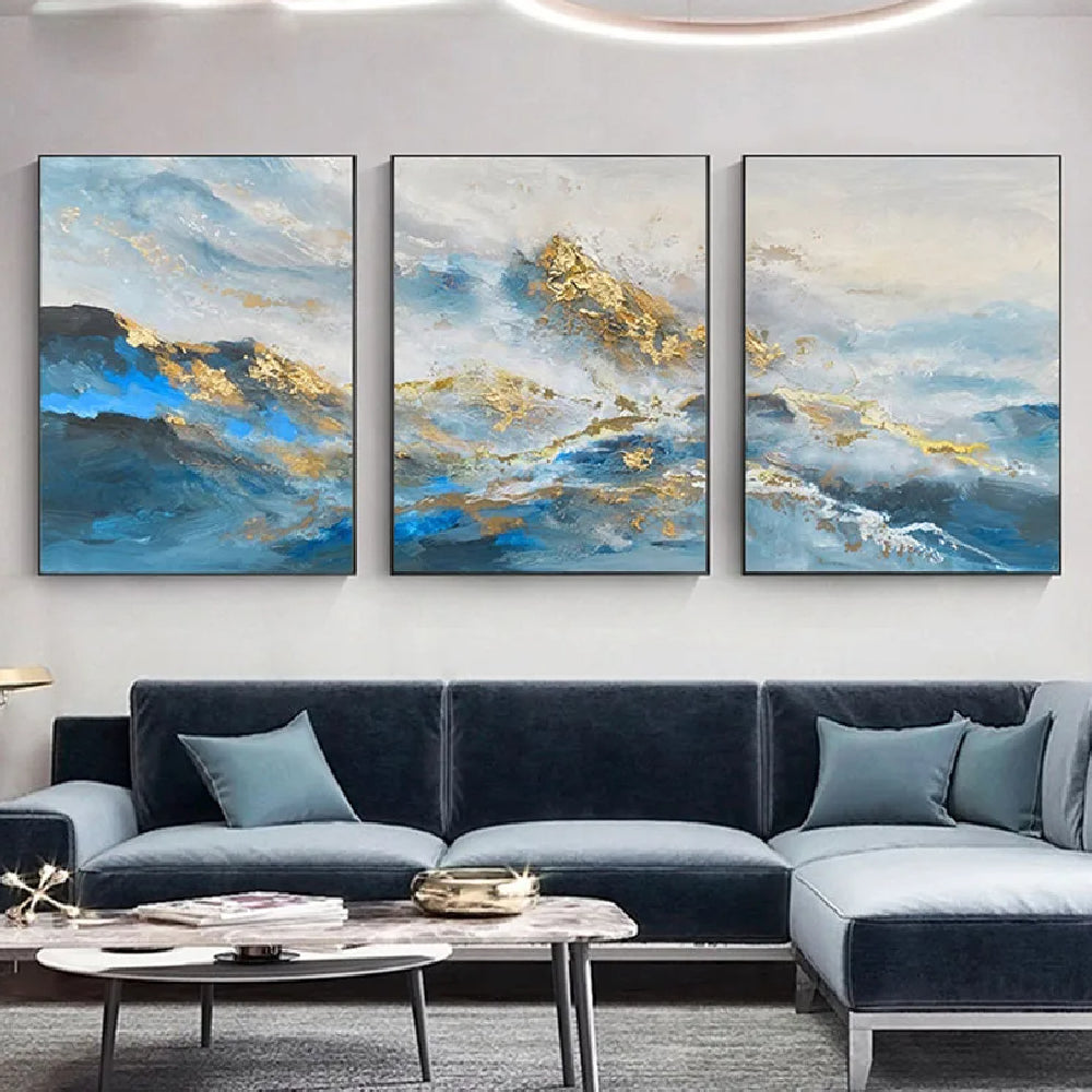 Room mockup showing three blue and white abstract mountain-like landscapes with gold-coloured textured peaks and sweeping water-like bands.