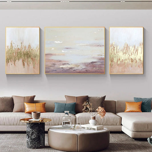 Room mockup showing three pale blush and cream abstracts with gold-coloured textured marks; the centre has soft horizontal mauve bands.