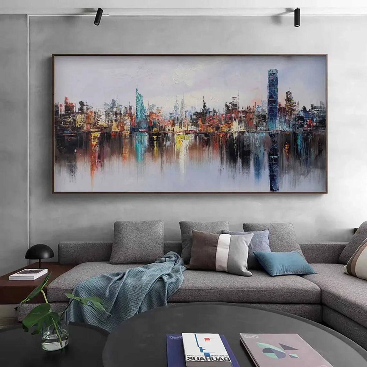Room mockup showing colourful city skyline with a tall blue tower and long vertical reflections in calm water beneath a pale sky.