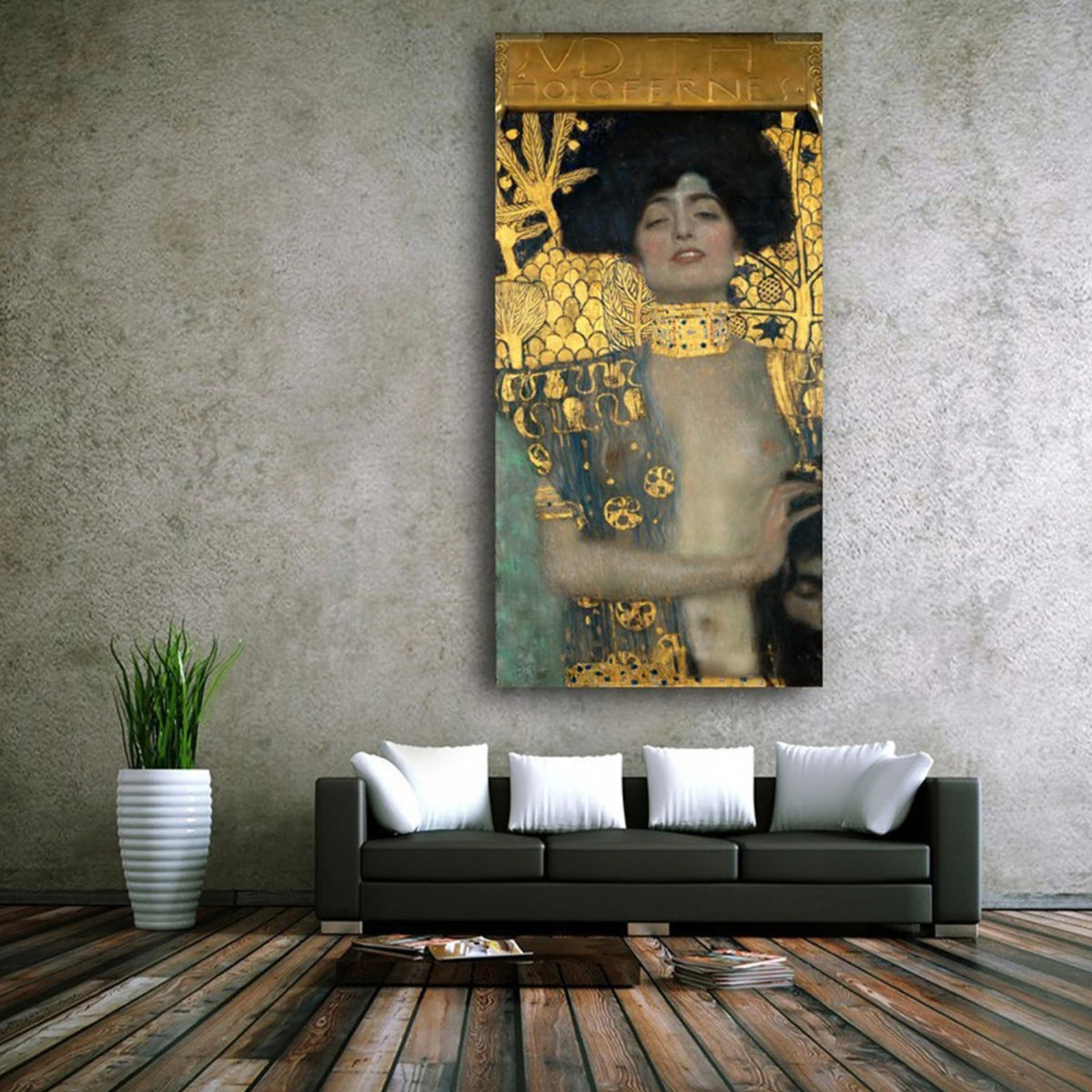 Gold-patterned woman portrait above a black sofa with white cushions against a grey wall.
