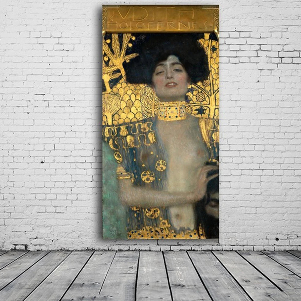 Gold-patterned woman portrait displayed against a white brick wall above a grey plank floor.