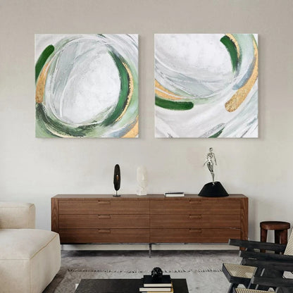 Room mockup showing two abstract paintings with looping green and grey strokes and gold-coloured accents over white fields.