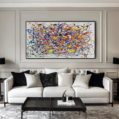 Wide horizontal abstract expressionist painting with colorful splashes displayed above a white sofa in a black and white luxury living room.