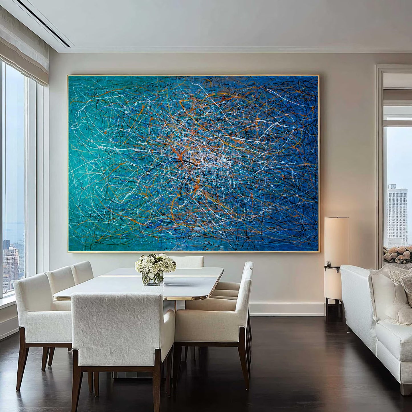 Modern living room with a large abstract blue painting, white furniture, and cityscape view.