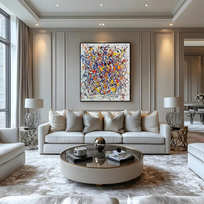 Modern abstract splatter painting mounted on a neutral panelled wall above a cream sofa in an elegant classic living room.