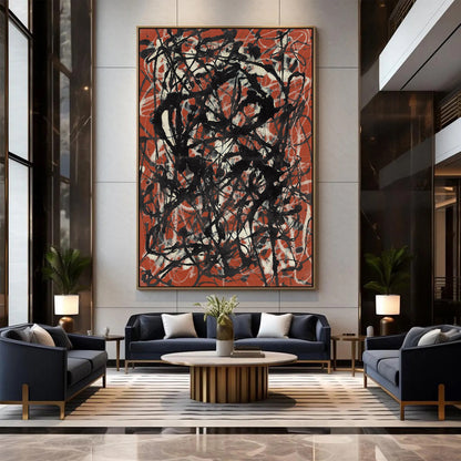 A large framed abstract wall art piece with black, white, and rust-orange scribbled brushstrokes hangs in a modern living room above a dark blue sofa and striped rug.