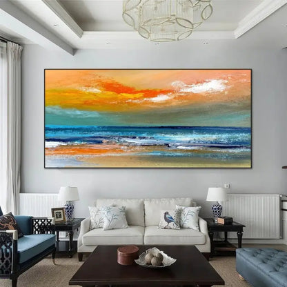 Room mockup showing broad orange sunset sky with white clouds above blue-grey sea and a warm sandy foreground.