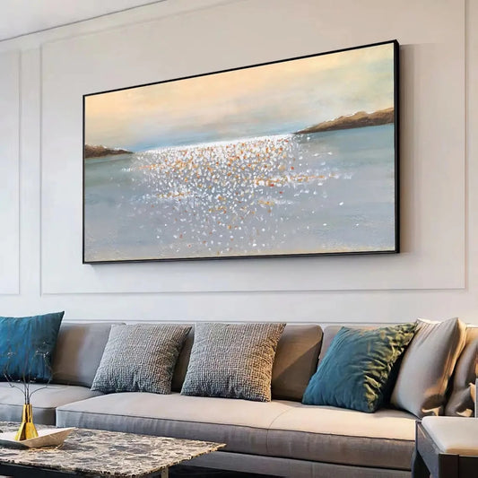 Room mockup showing pale blue-grey water with small cream and gold-coloured reflective dabs between distant dark shores beneath a peach-grey sky.