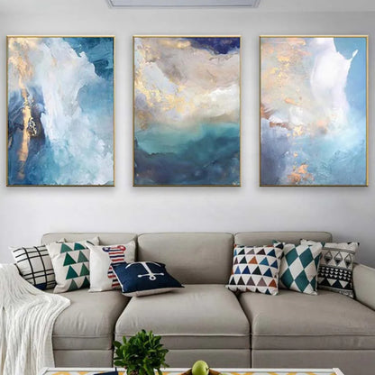 Room mockup showing three abstract panels with cloudy white and pale blue fields, deep teal areas and gold-coloured accents.
