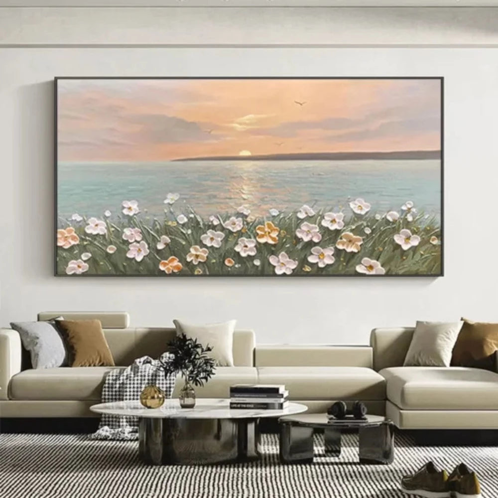 Room mockup showing pink and white flowers on green stems beside calm blue-grey sea beneath a peach sunset and low pale sun.