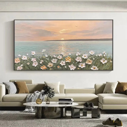 Room mockup showing pink and white flowers on green stems beside calm blue-grey sea beneath a peach sunset and low pale sun.