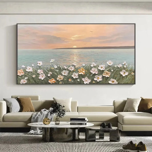 Room mockup showing pink and white flowers on green stems beside calm blue-grey sea beneath a peach sunset and low pale sun.