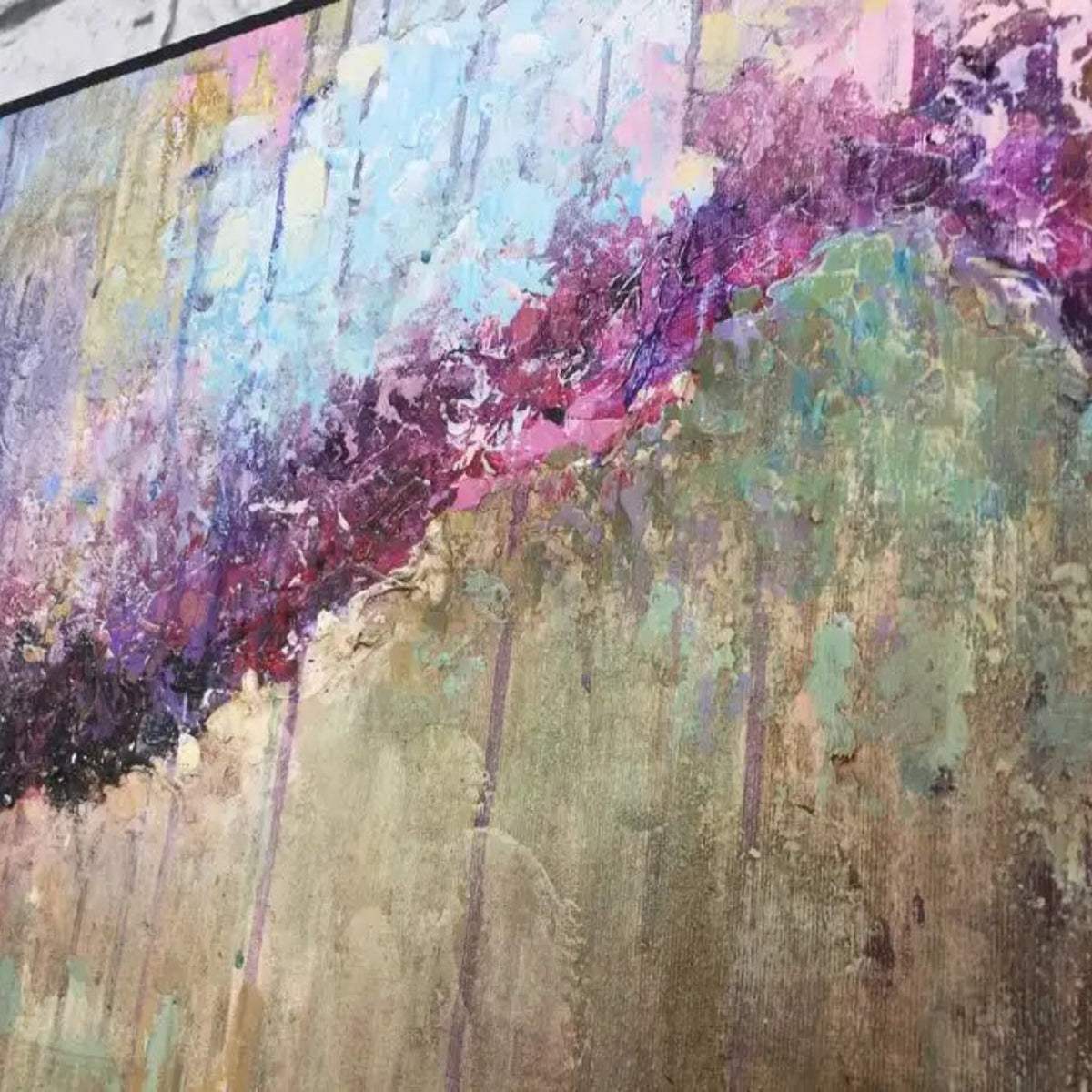 Close-up. A dark purple diagonal band crosses pale blue, pink and green textured areas with fine vertical drips.