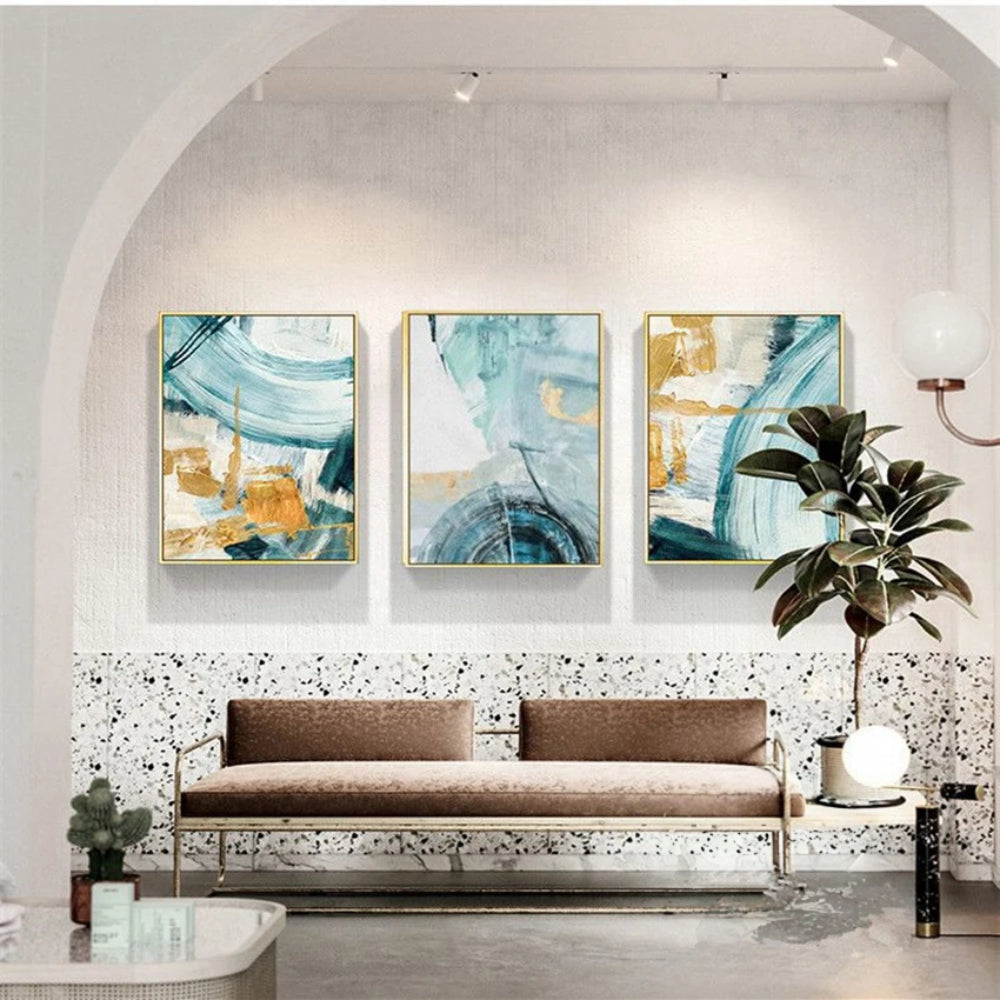 Room mockup showing three abstracts with sweeping teal and pale blue arcs over cream fields with gold-coloured geometric accents.