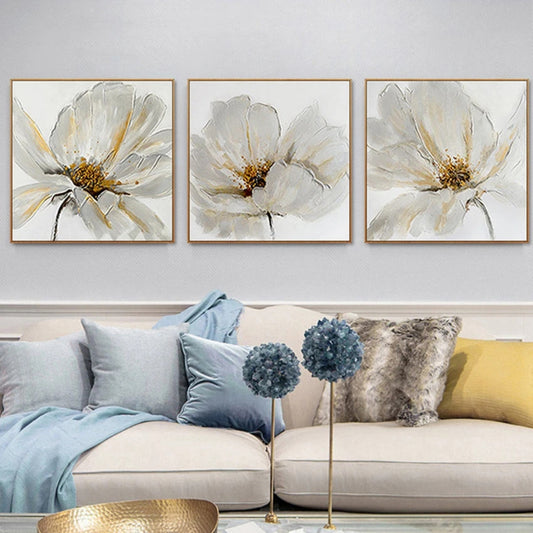 Room mockup showing three white flower paintings with fine grey petal outlines and gold-coloured centres on pale backgrounds.