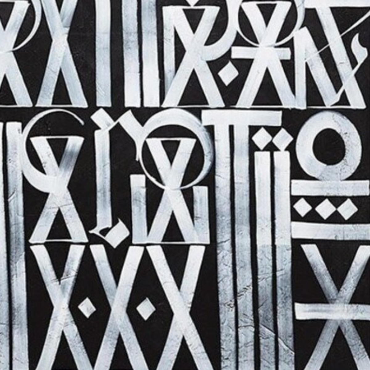 Close-up. White circles, triangles and elongated letter-like symbols arranged in rows across grey.