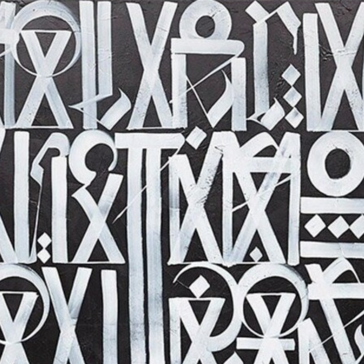 Close-up. White circles, triangles and elongated letter-like symbols arranged in rows across grey.
