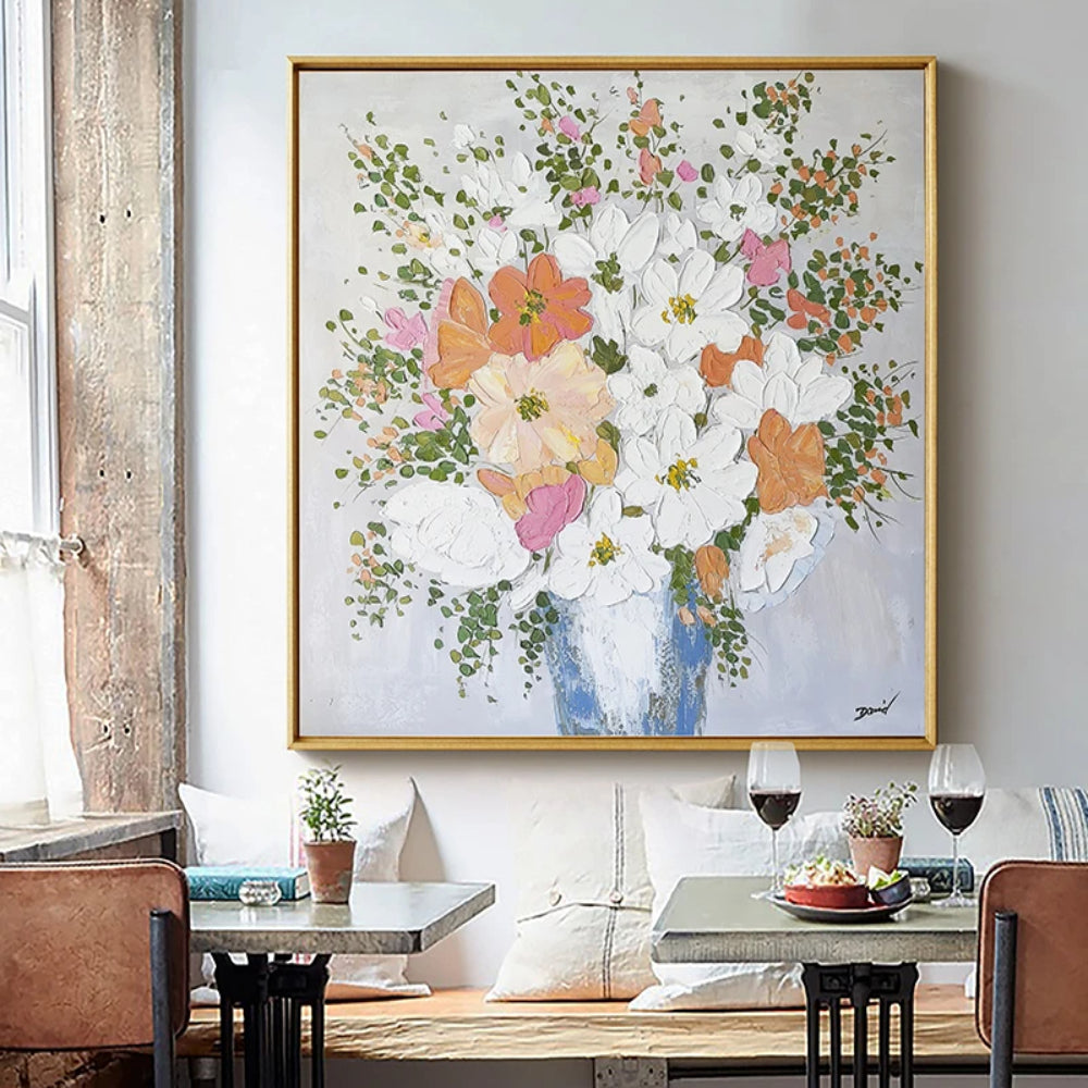 Room mockup showing white, pale pink and orange flowers with small green leaves in a blue vase on a pale grey background.