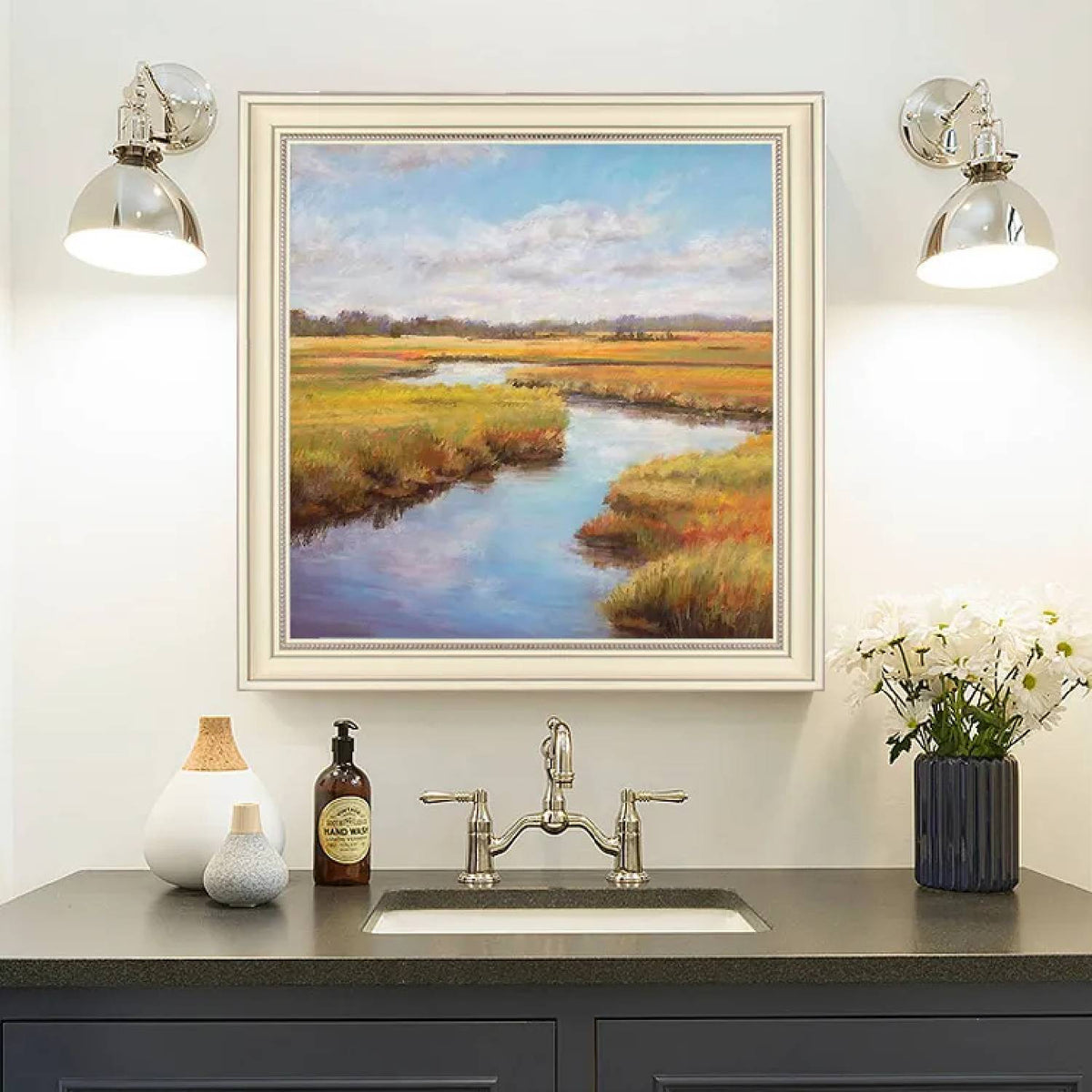 Room mockup. A winding blue stream runs through ochre and green marsh grasses beneath a pale blue sky with soft white clouds.