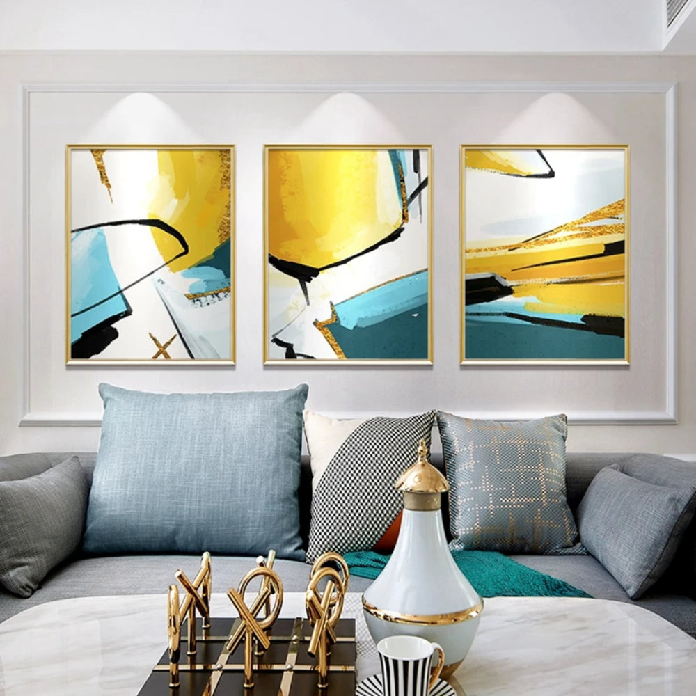 Room mockup showing three abstracts with bold yellow, teal and white geometric fields crossed by sweeping black lines.