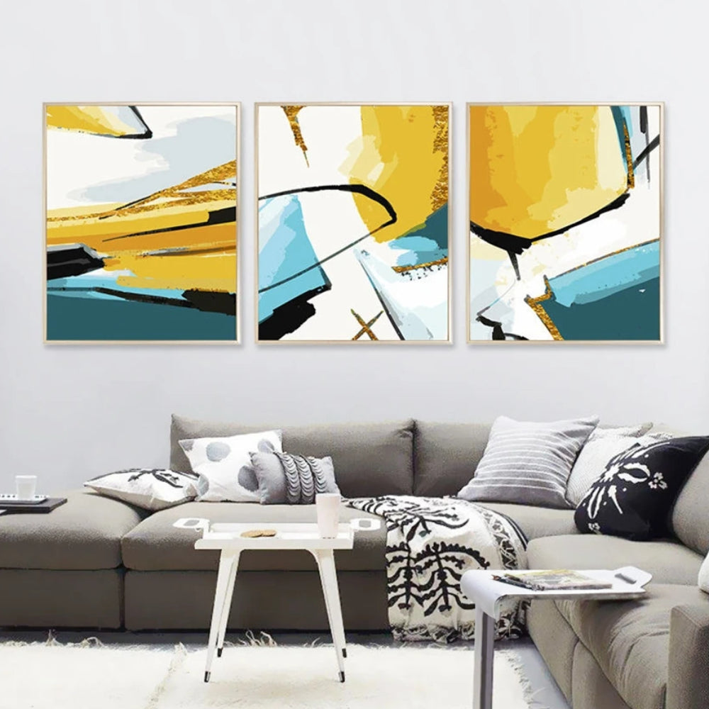 Room mockup showing three abstracts with bold yellow, teal and white geometric fields crossed by sweeping black lines.