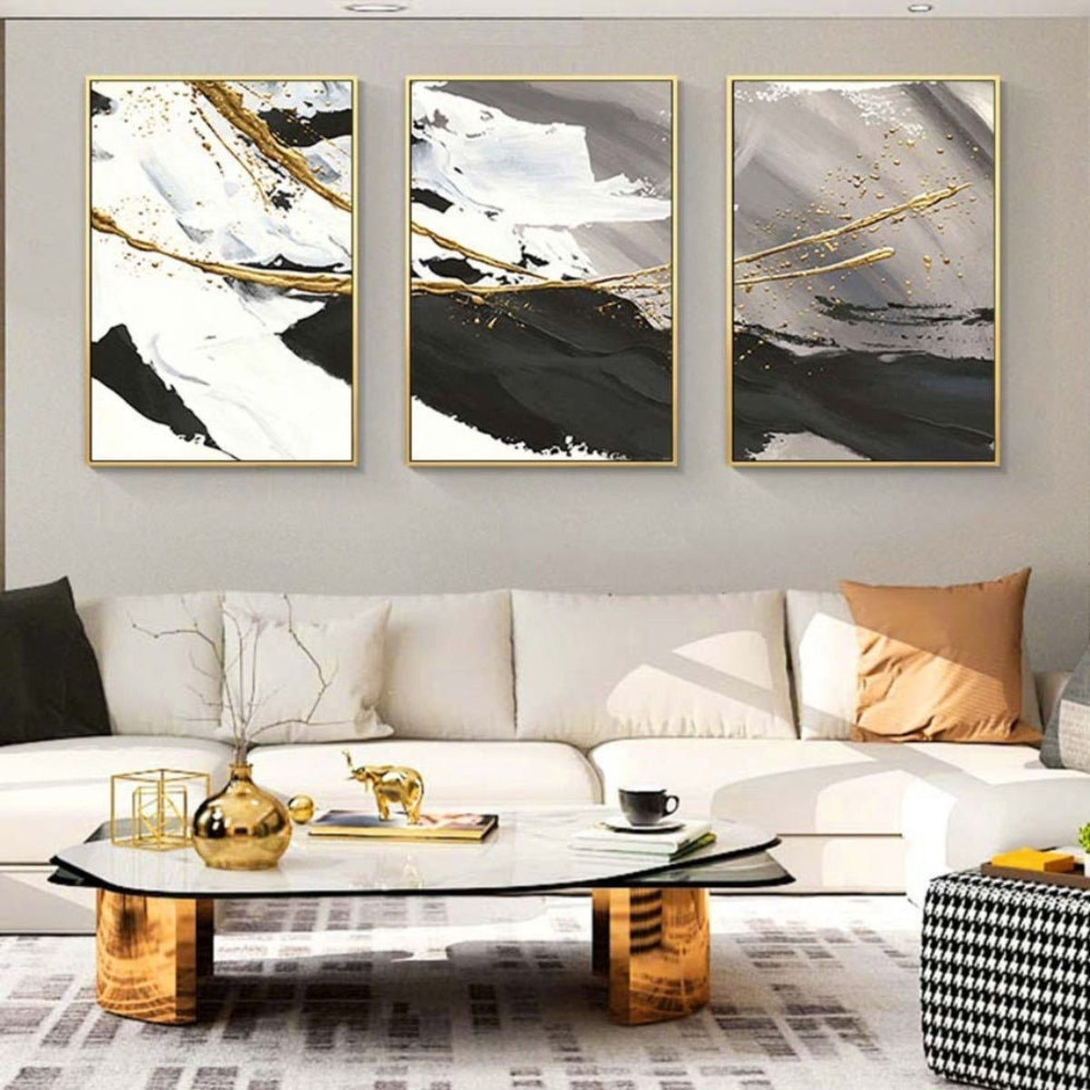 Room mockup. Three-panel artwork with sweeping black, white and grey strokes crossed by fine gold-coloured curves.