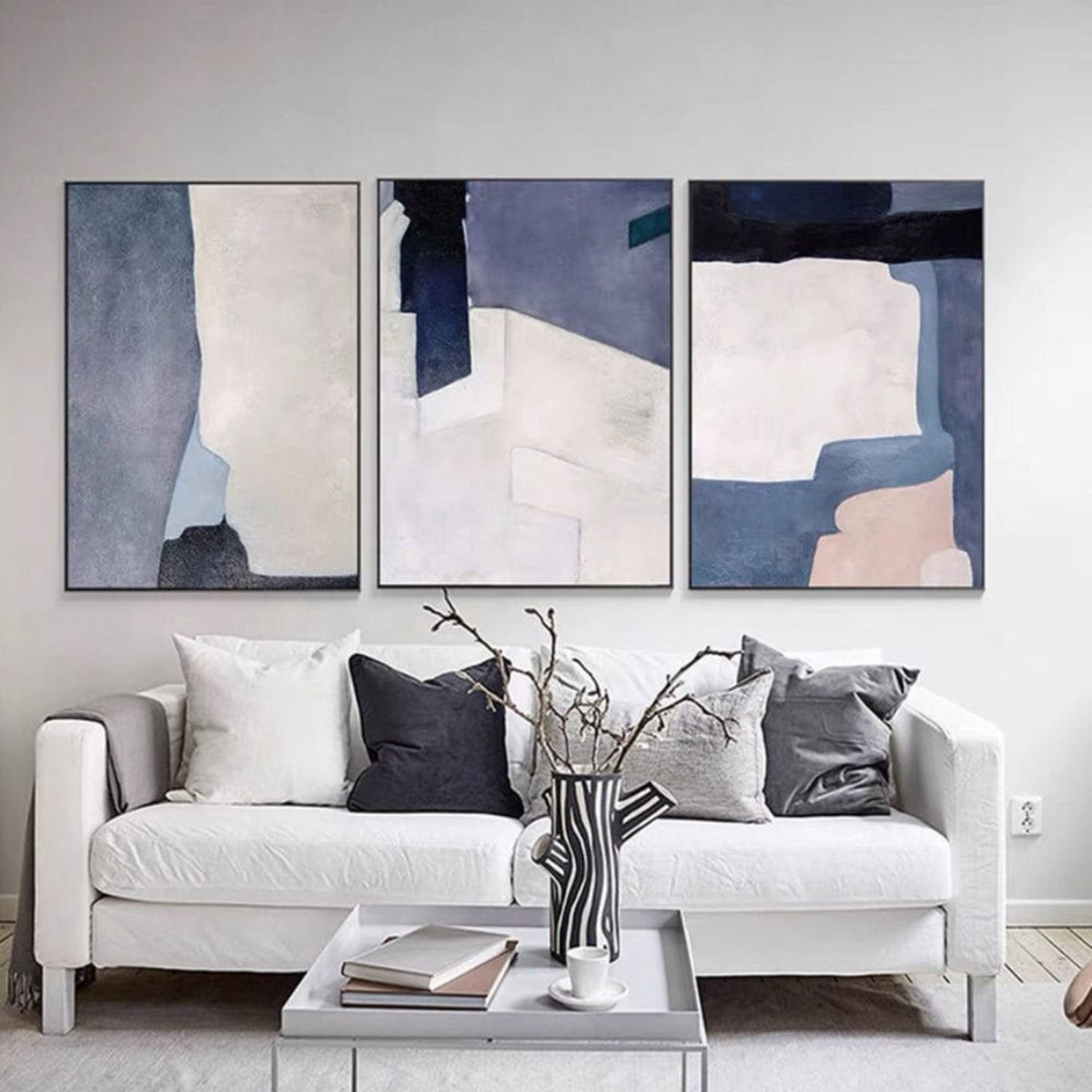 Room mockup. Three-panel abstract artwork with large slate blue, grey, white and pale pink geometric fields.