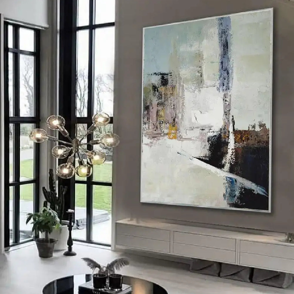 Room mockup showing cream abstract painting with pale blue-grey blocks, a tall dark streak and black and brown angular lower shapes.