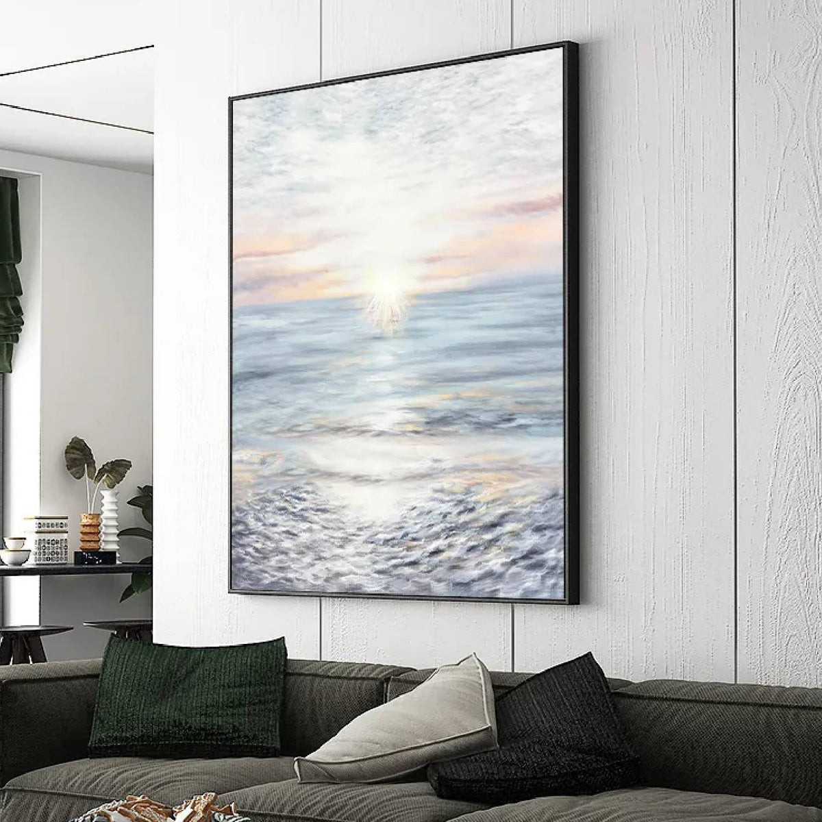 Room mockup. A pale sun near the horizon casts a bright reflection across blue-grey water beneath a softly pink and white sky.