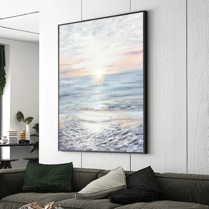 Room mockup. A pale sun near the horizon casts a bright reflection across blue-grey water beneath a softly pink and white sky.