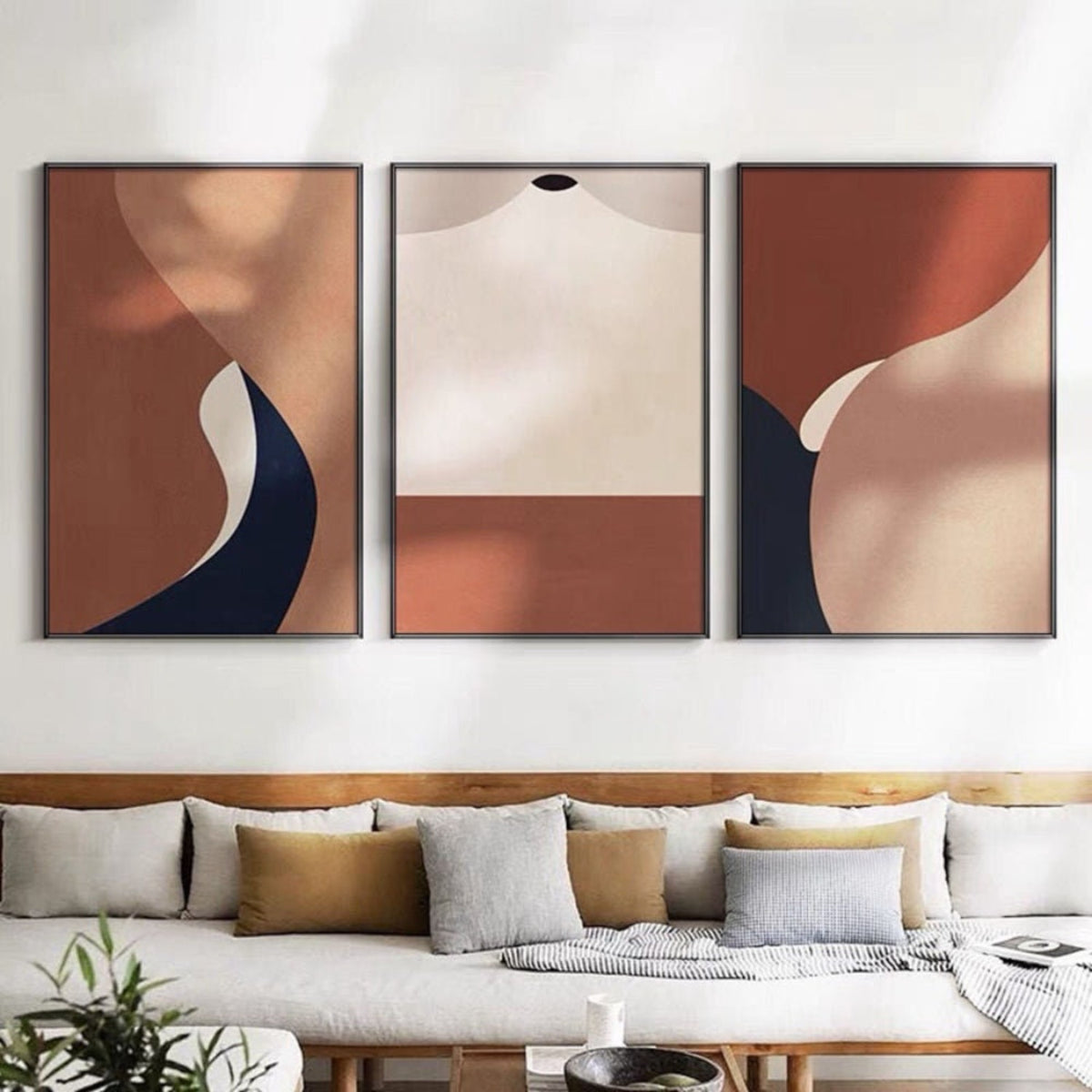 Room mockup. Three-panel abstract artwork with terracotta, cream and navy curved geometric shapes.